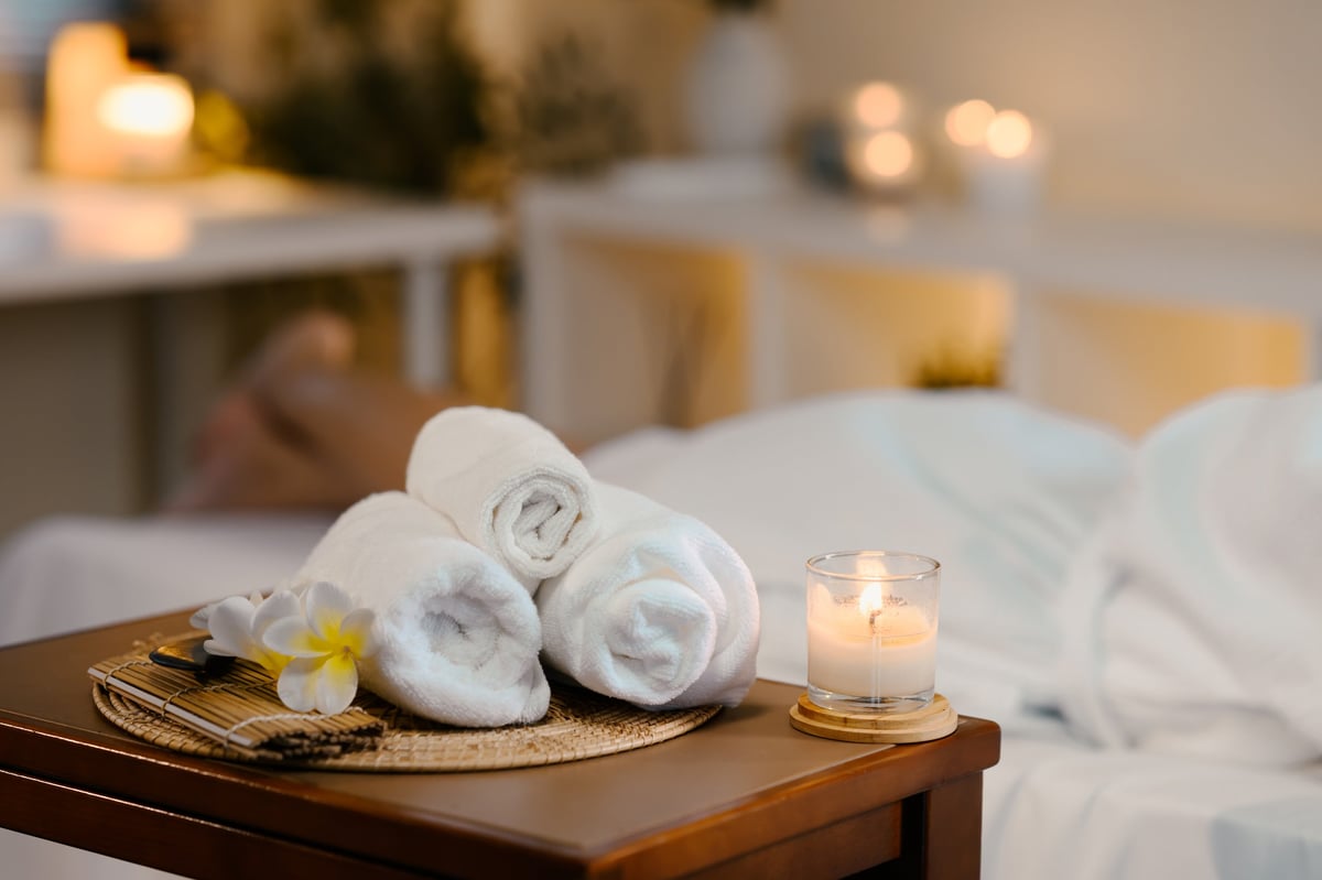 Serene spa room with rolled towels, candle, and soft natural decor