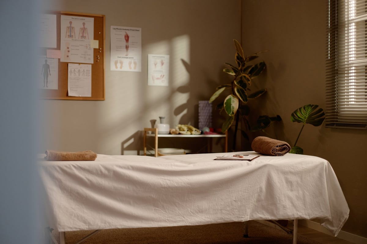 Wide shot of a serene massage therapy room featuring treatment table, folded towels, and calming wellness decor